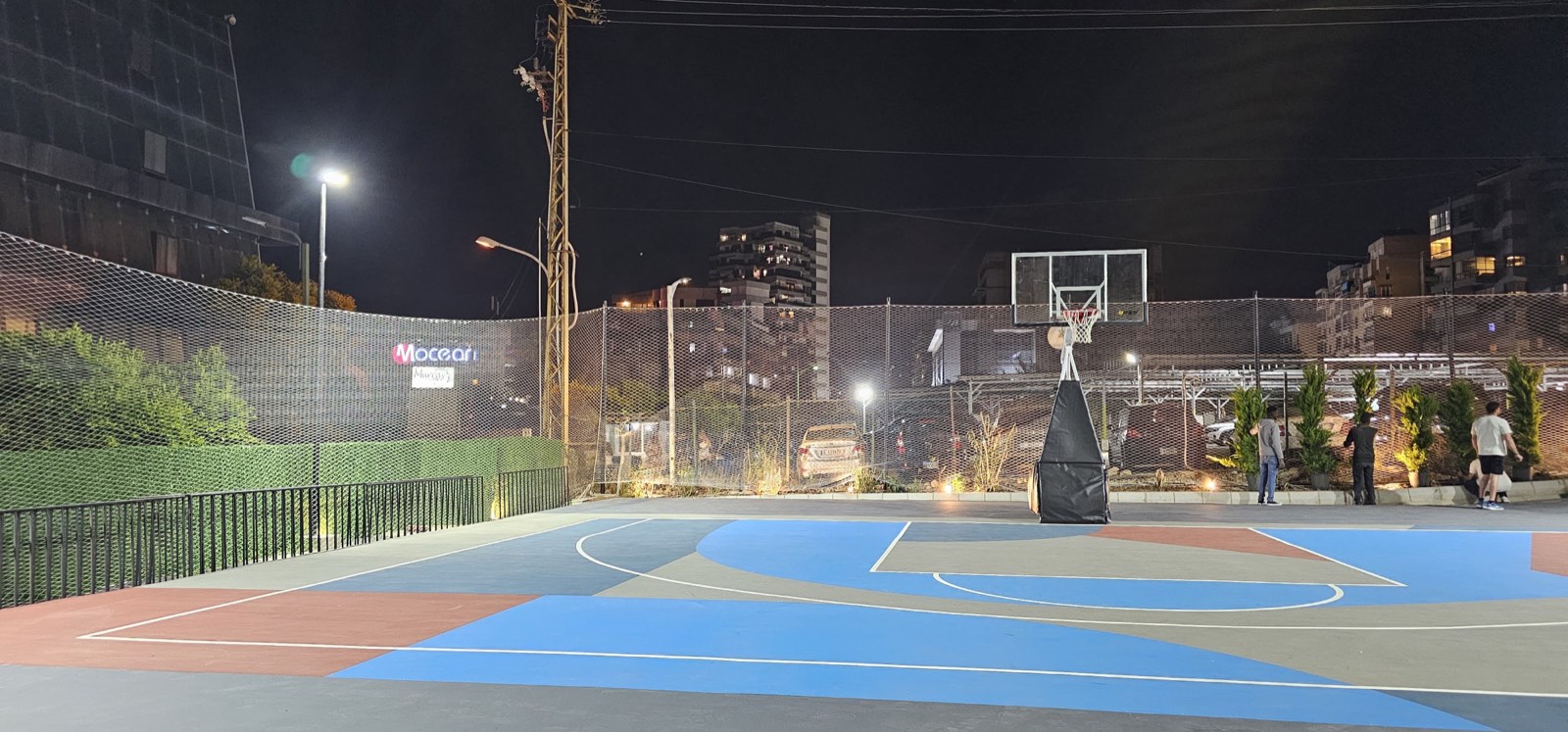 Basketball court with full perimeter net enclosure at night in Lebanon