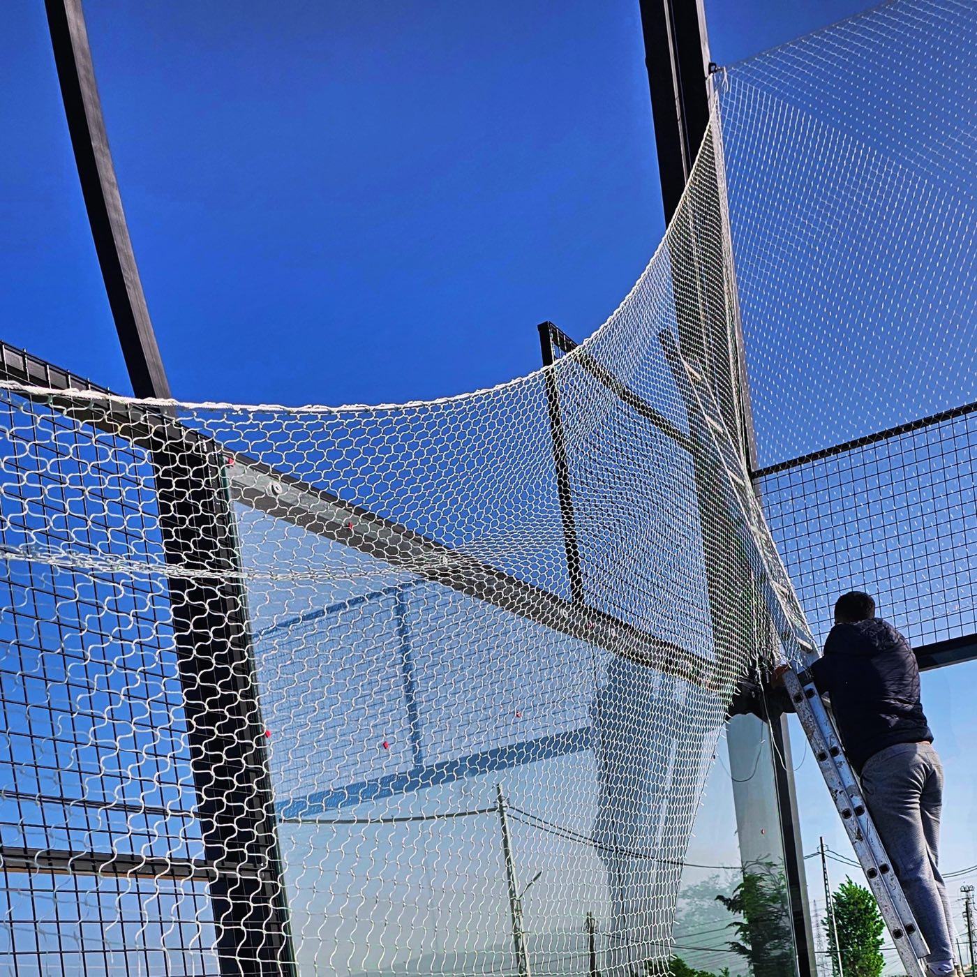 TurfFix Pro worker tensioning a new perimeter net on a court in Lebanon