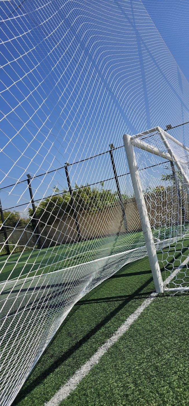 White perimeter netting behind a goal on a green turf court in Lebanon